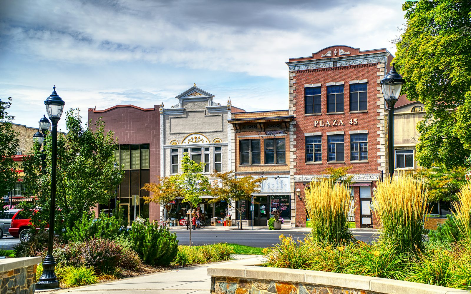 Row of restored brick storefront buildings on a landscaped main street